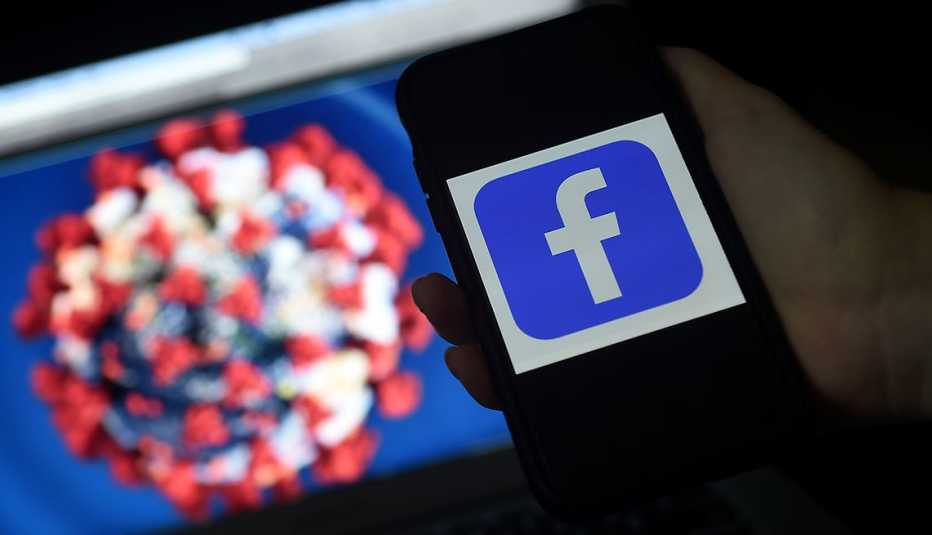 El logo de Facebook en un teléfono y de fondo un gráfico del coronavirus El logo de Facebook en un teléfono y de fondo un gráfico del coronavirus