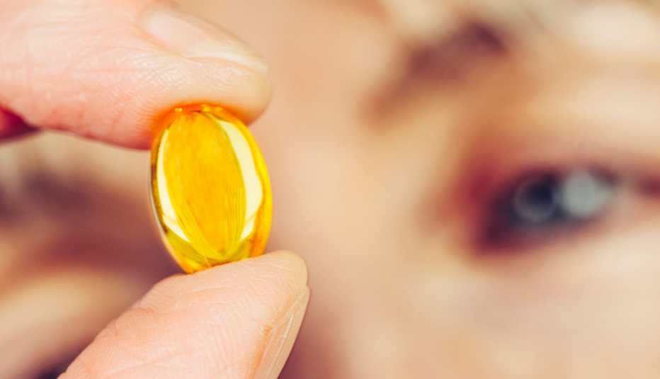 Una mujer sostiene una vitamina entre su dedo pulgar e índice