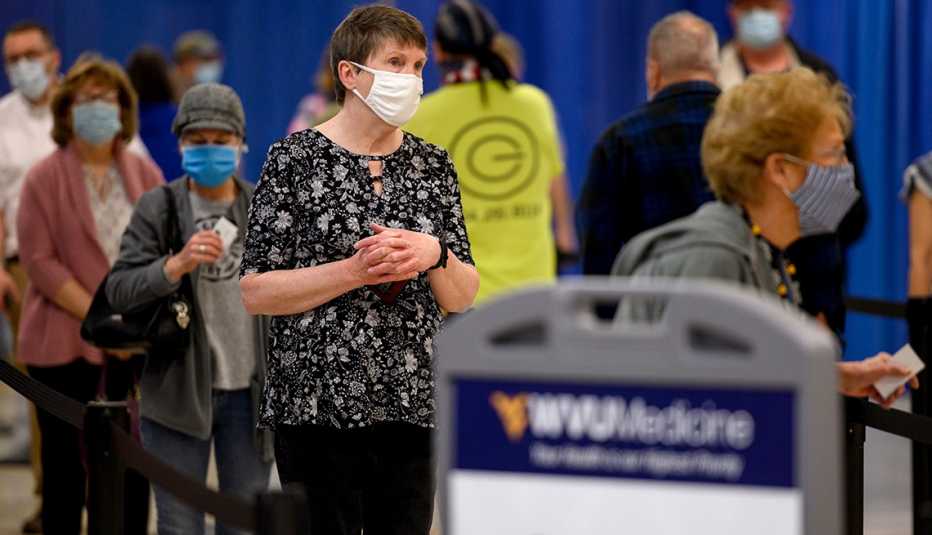 Personas con máscaras protectoras esperan ser vacunados contra la COVID-19 Personas con máscaras protectoras esperan ser vacunados contra la COVID-19