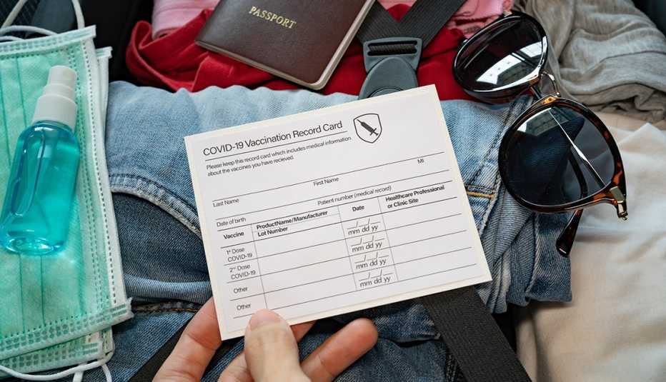 Una mujer coloca su tarjeta de vacunación junto con otros accesorios en una maleta
