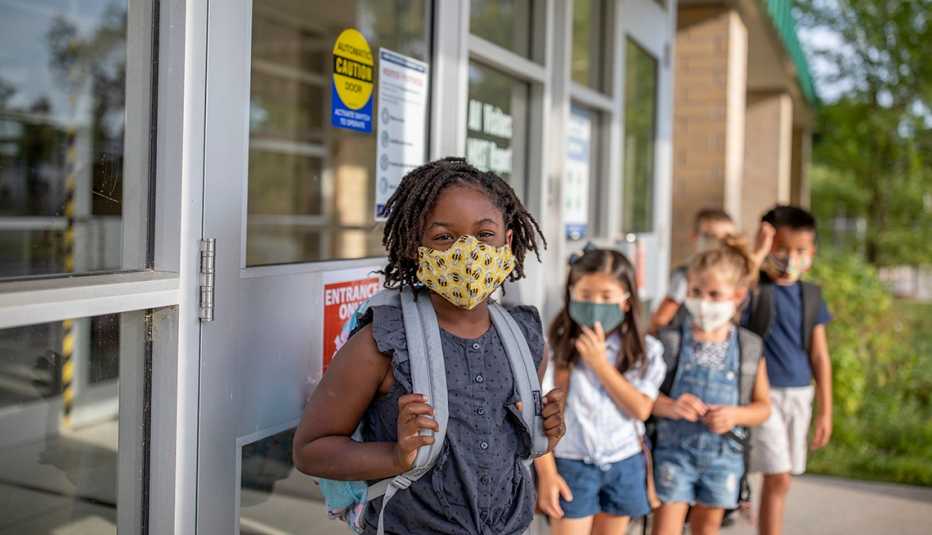 Grupo de niños en fila, cada uno con su mascarilla y listos para entrar a un salón de clases Grupo de niños en fila, cada uno con su mascarilla y listos para entrar a un salón de clases