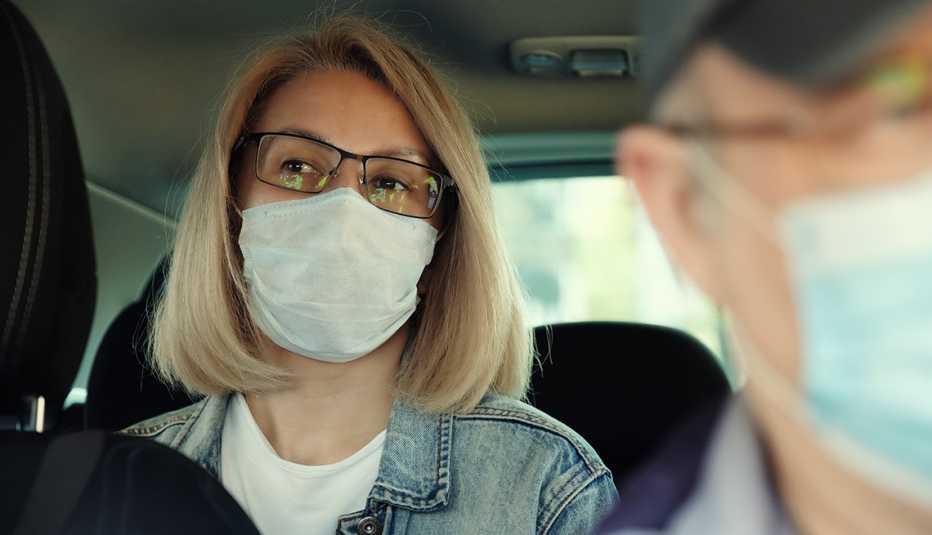 Una mujer en un taxi con una mascarilla Una mujer en un taxi con una mascarilla