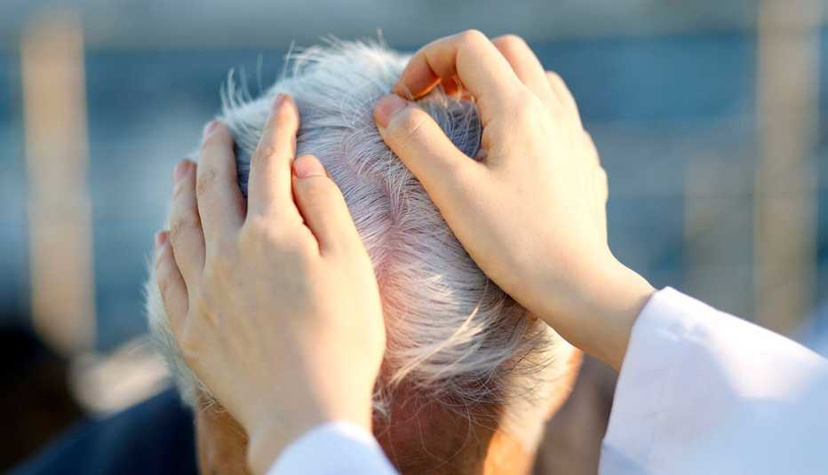 Doctora revisa el cuero cabelludo a un hombre. Doctora revisa el cuero cabelludo a un hombre.
