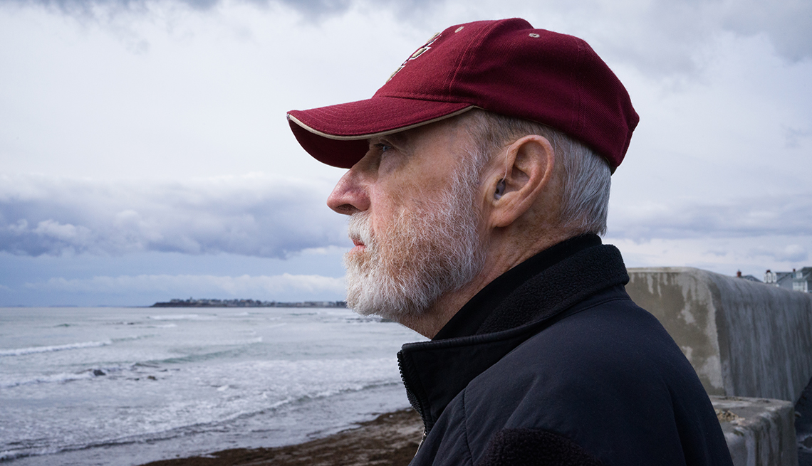 Un hombre con audífonos para la sordera observa el mar