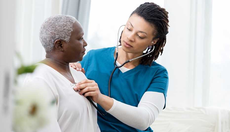 Una doctora usa un estetoscopio para escuchar el corazón de su paciente Una doctora usa un estetoscopio para escuchar el corazón de su paciente