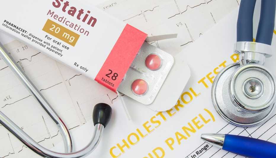 Empaque de estatinas abierto, un estetoscopio y documentos médicos