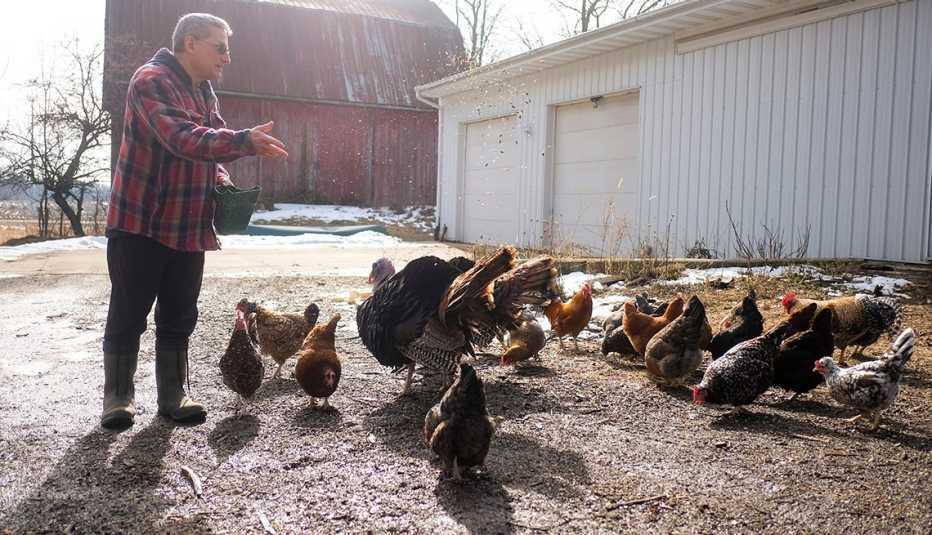 Un hombre alimenta a sus aves en su granja