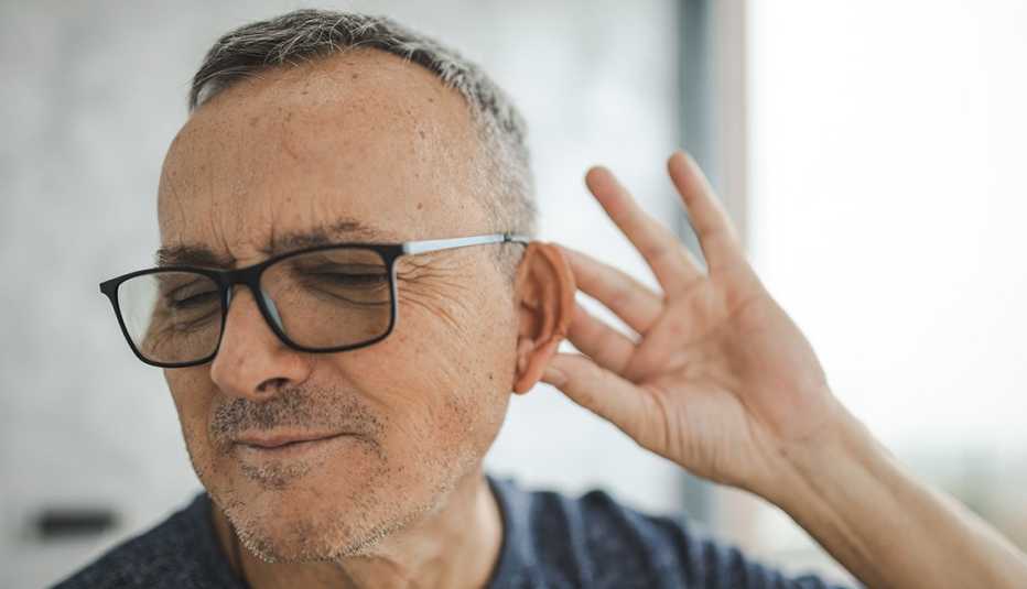 Un hombre con su mano en su oreja para escuchar mejor