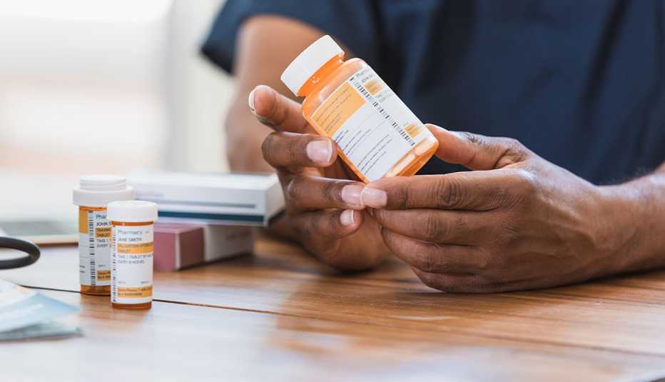 Un hombre examina un frasco de pastillas