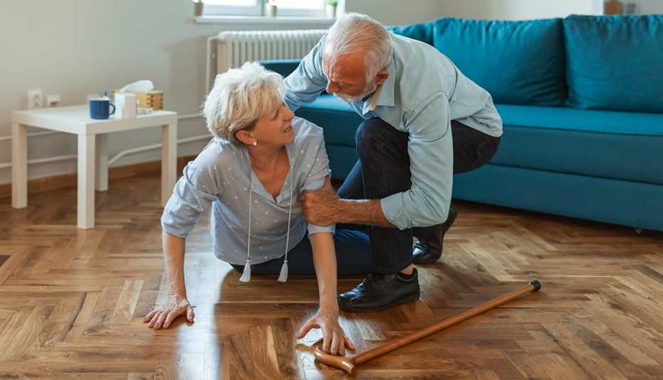 Esposo ayuda a su esposa que se ha caído en la sala de su casa Esposo ayuda a su esposa que se ha caído en la sala de su casa