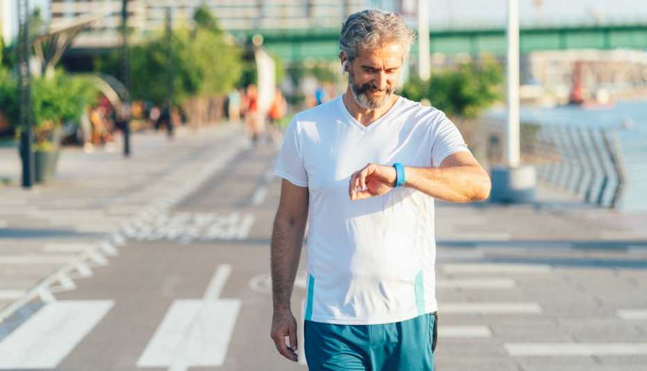 Un hombre mira su reloj inteligente para ver cuánto se ejercitó Un hombre mira su reloj inteligente para ver cuánto se ejercitó