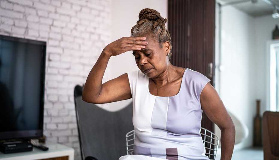 Una mujer con su mano en la frente en señal de dolor de cabeza