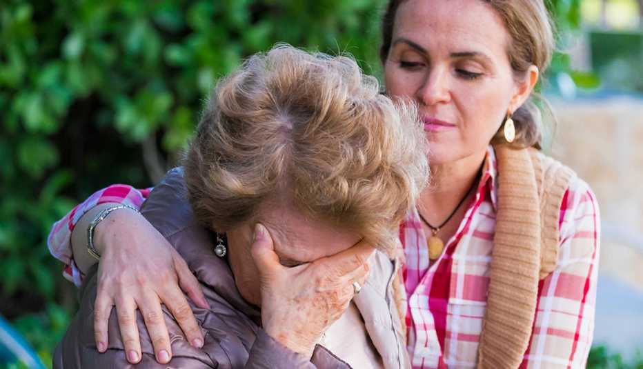 Una mujer mayor llorando siendo consolada por su hija.