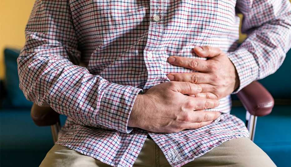 Hombre con sus manos en el abdomen en señal de dolor