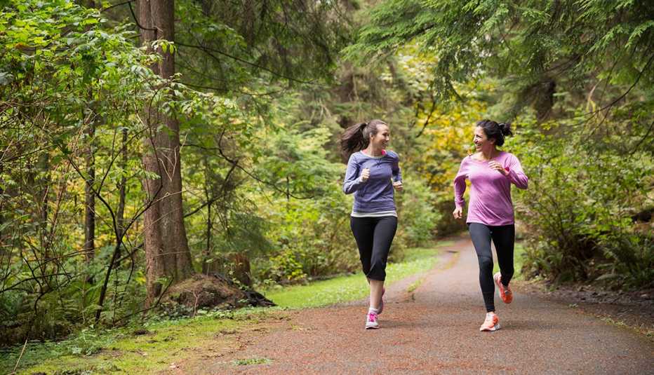 Dos mujeres corriendo por un camino forestal Dos mujeres corriendo por un camino forestal
