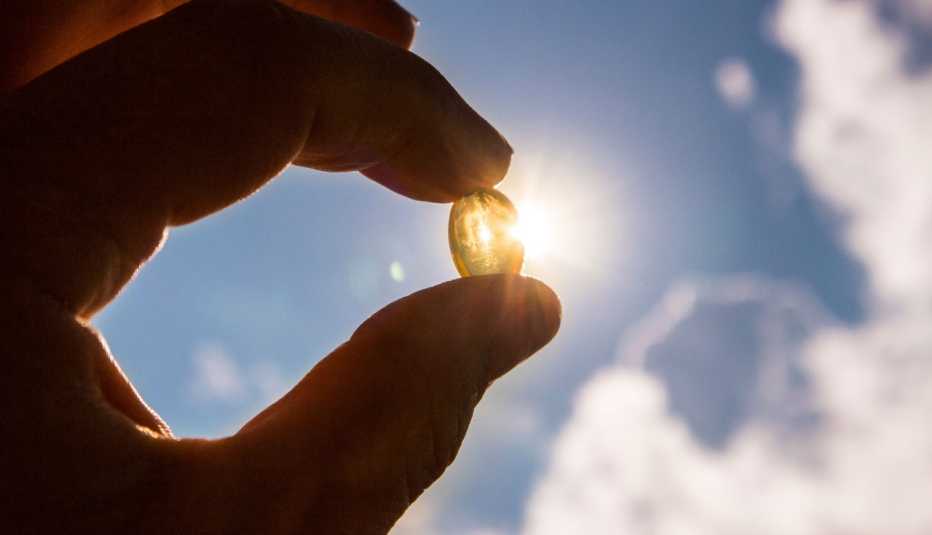 Manos sostienen una vitamina D contra el sol