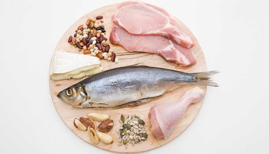 Carnes, pescado, granos y quesos sobre un picador de madera
