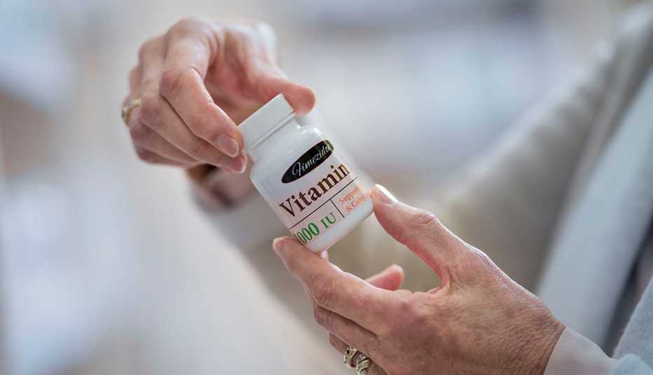 Una mujer examina un frasco de vitaminas