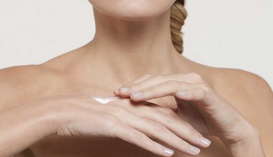 Mujer untándose una loción para el cuerpo Mujer untándose una loción para el cuerpo