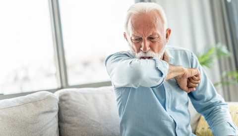 Un hombre tose en su codo Un hombre tose en su codo