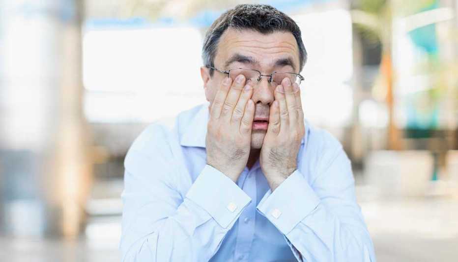 Hombre rascando sus ojos en señal de agotamiento Hombre rascando sus ojos en señal de agotamiento