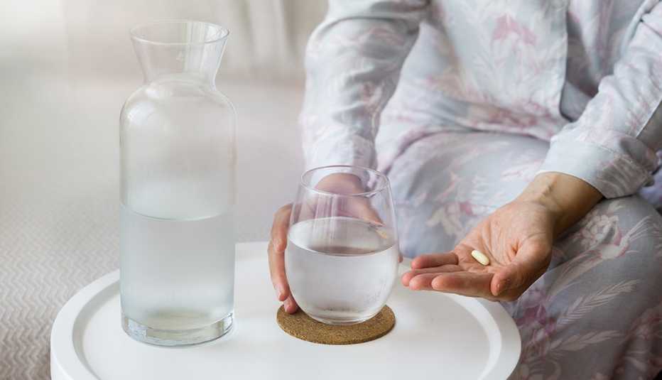 Mujer tomando su medicamento con agua Mujer tomando su medicamento con agua