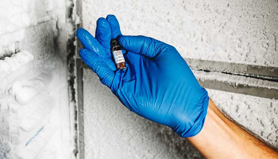 Una persona usa un guante médico azul y sosteniene una muestra de sangre