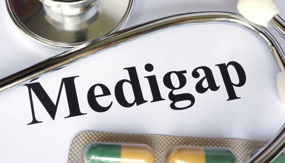 Un estetoscopio y unas pastillas sobre un papel que dice Medigap