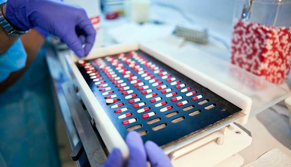 Empleado de farmacéutica colocando medicamentos en una bandeja