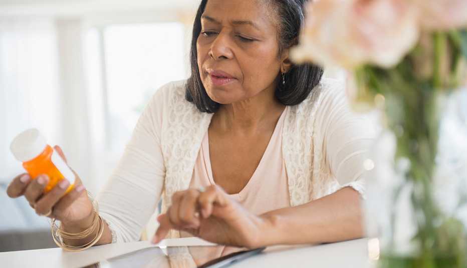 Mujer leyendo las instrucciones en un frasco de pastillas
