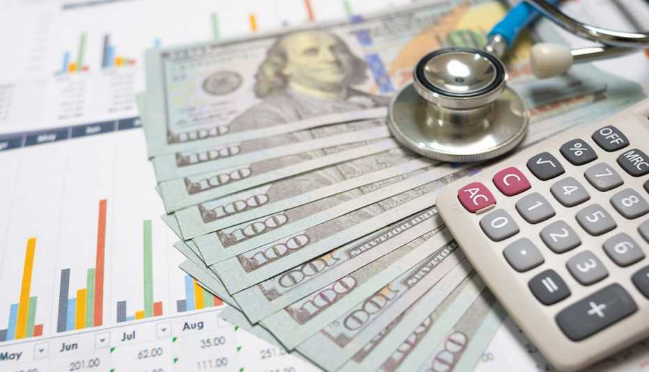 Una hoja de papel con unas gráficas, dinero, un estetoscopio y una calculadora