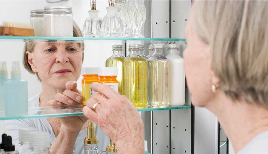 Mujer tomando un frasco de medicamentos de su botiquín