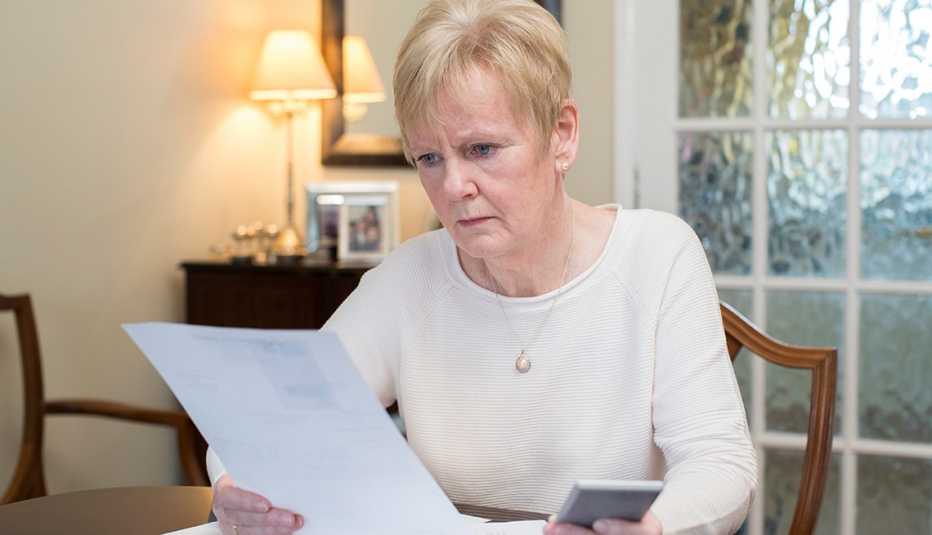 Mujer mirando un papel con cara preocupada