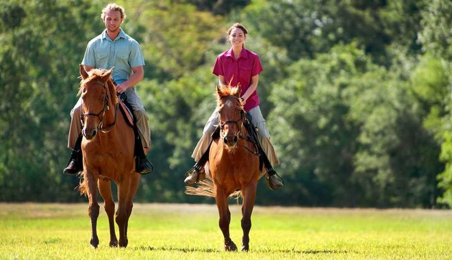 Pareja montando a caballo en un bosque