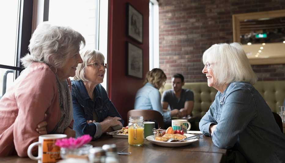Tres mujeres comparten en un restaurante.