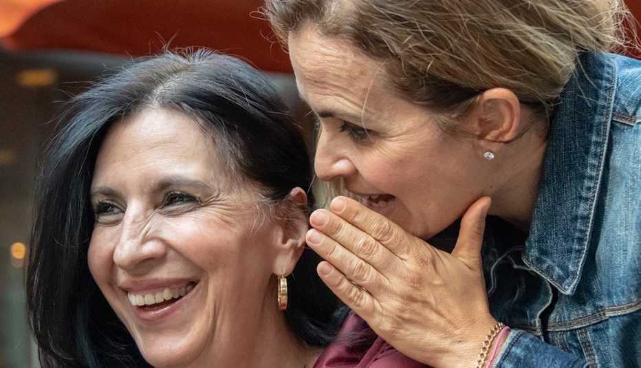 Una mujer susurra al oído de otra mujer