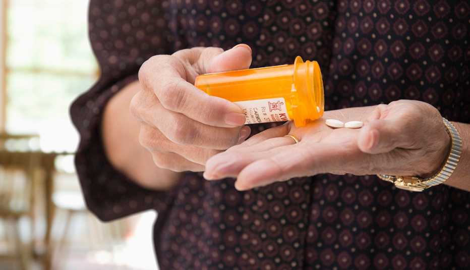 Mujer mayor con un tarro con pastillas en la mano.