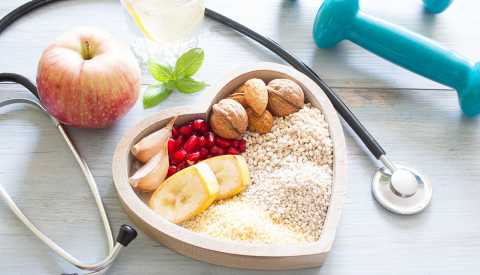 Una manzana, un estetoscopio, unas pesas libres y un plato en forma de corazón con alimentos saludables Una manzana, un estetoscopio, unas pesas libres y un plato en forma de corazón con alimentos saludables