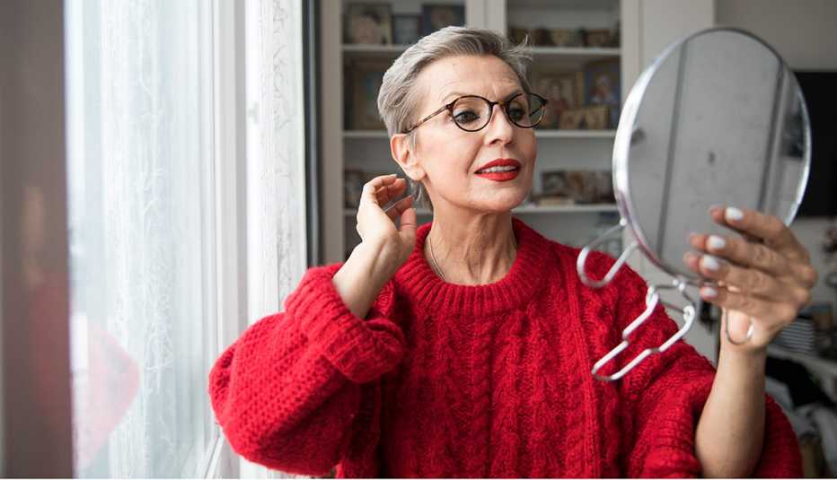 Mujer revisando su cabello en el espejo.