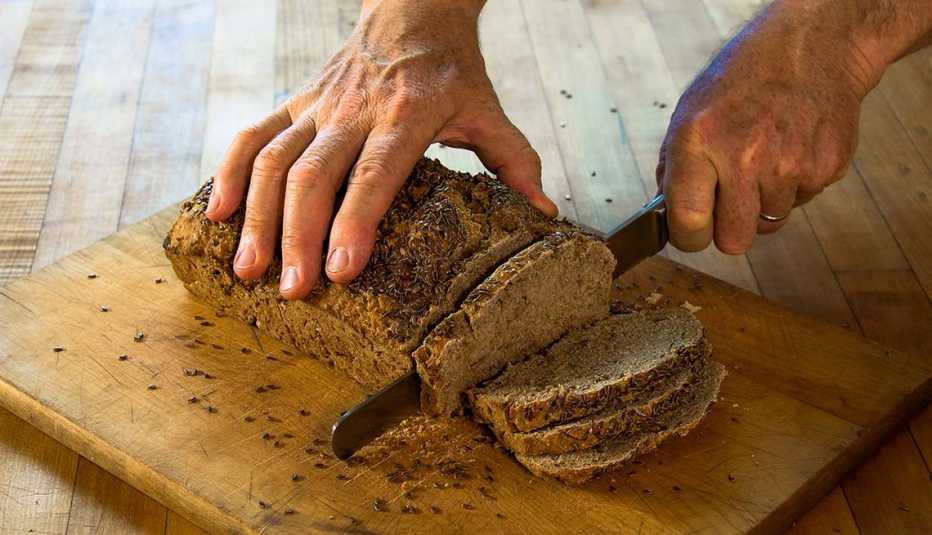 Persona rebanando un pan