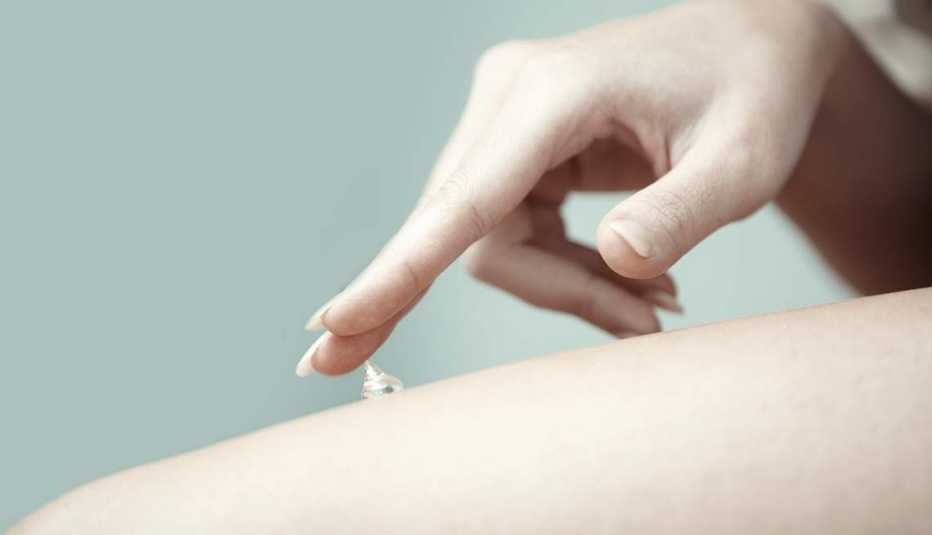 Mujer untándose crema en el cuerpo