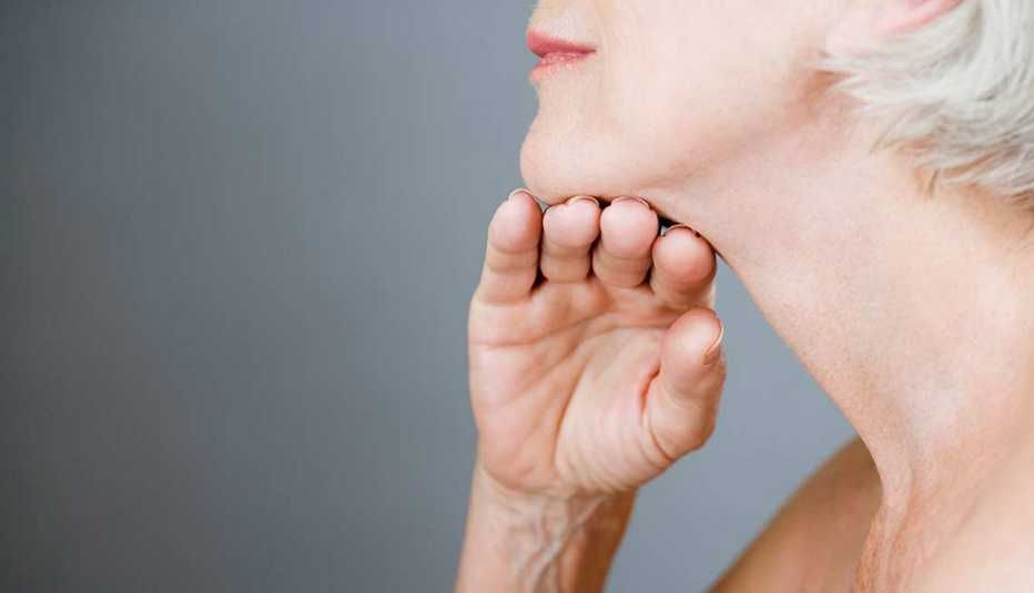 Mujer levantándose la quijada con la mano
