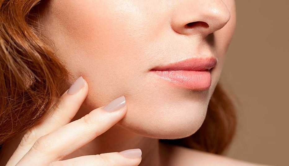 Mujer tocándose la cara - Preguntas al cirujano plástico