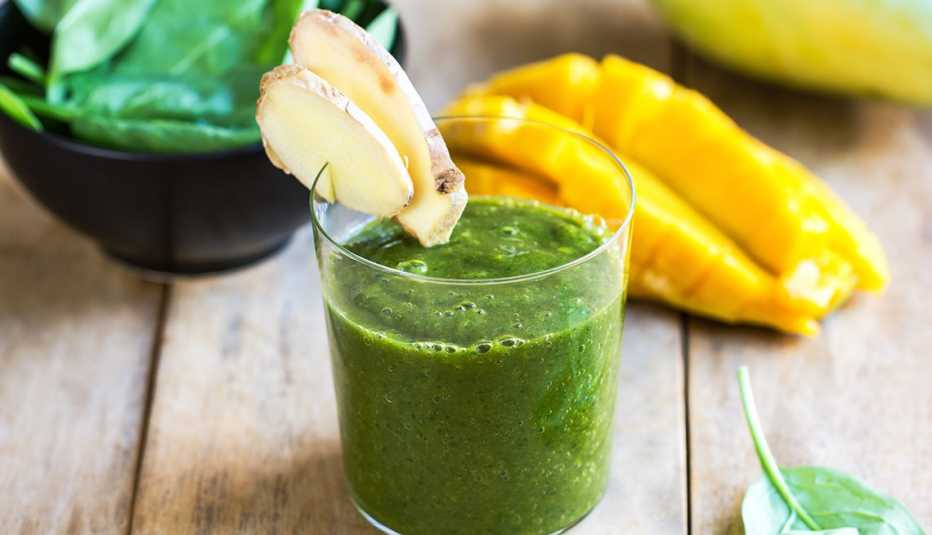 Vaso con un jugo verde decorado con rebanadas de pera - Cómo reacciona tu cuerpo ante un detox