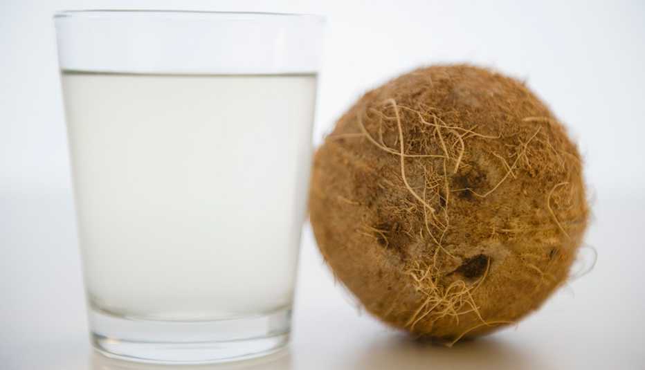 Vaso con agua de coco y un coco entero