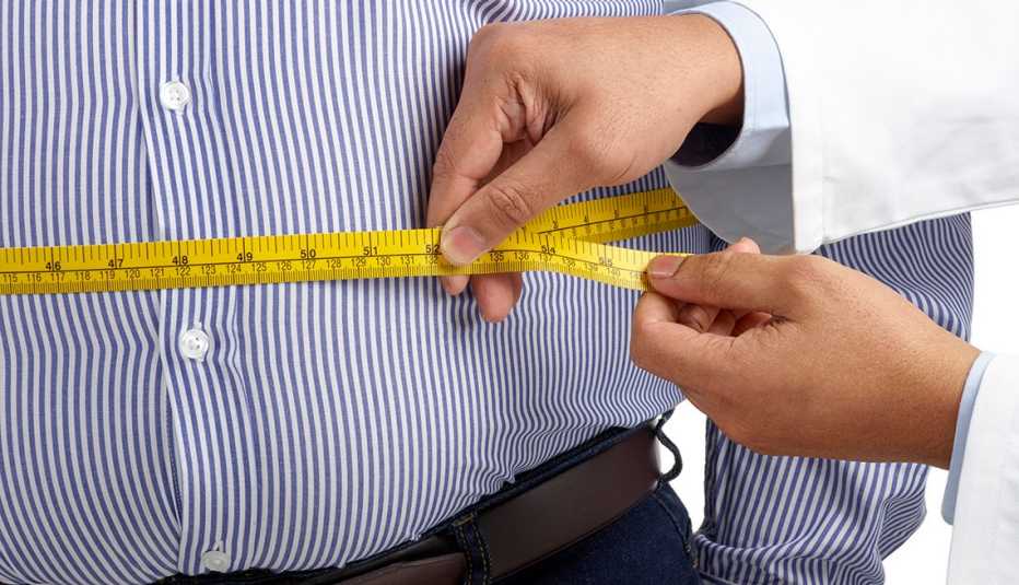 Doctor toma la medida del abdomen de un paciente Doctor toma la medida del abdomen de un paciente