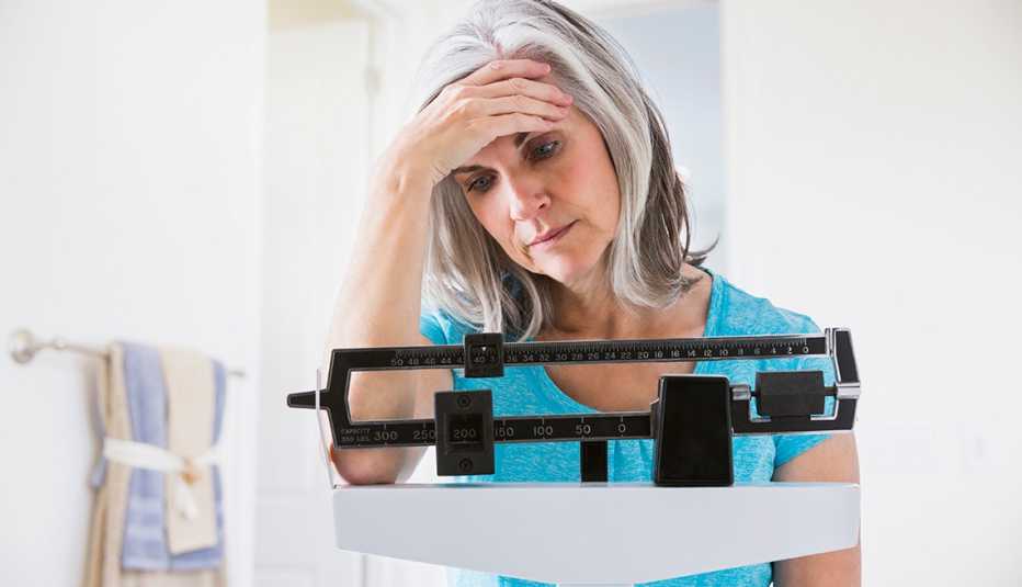 Mujer pesándose y preocupada por su peso 