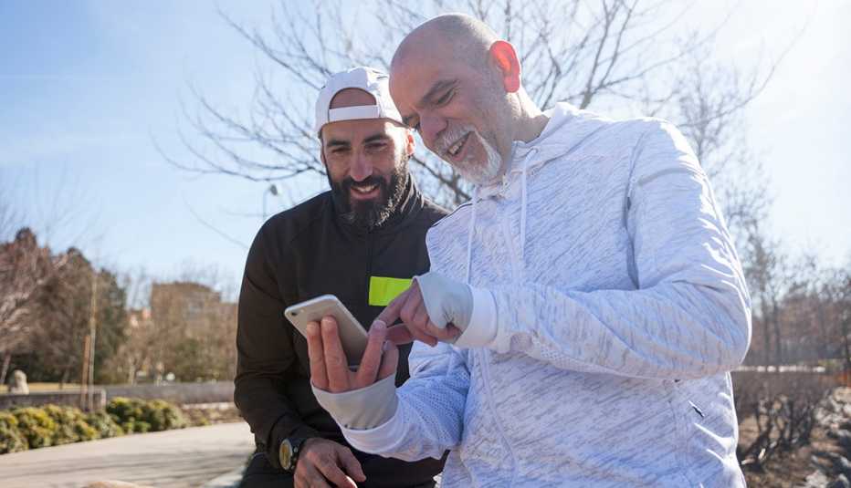 Dos hombres se ejercitan al aire libre mientras miran teléfono