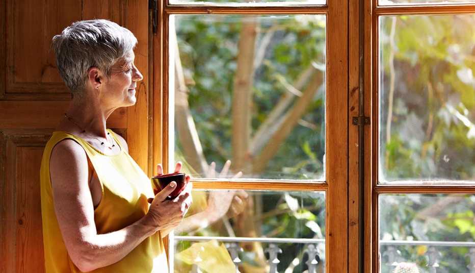 Mujer tomando café frente a una ventana
