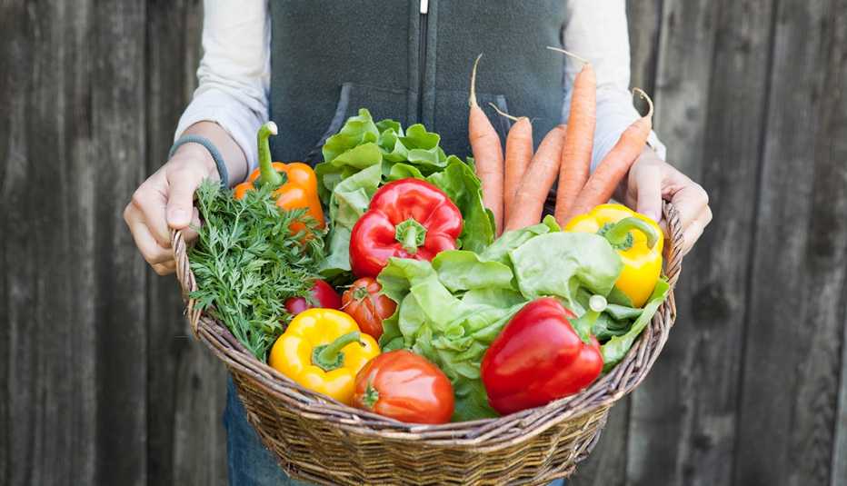 Mujer sosteniendo una canasta con vegetales